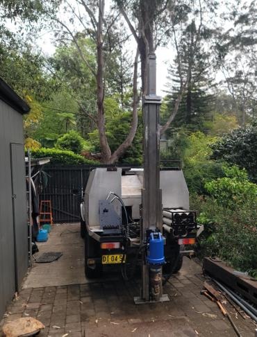 Landcruiser-mounted auger and DCP rig with the mast raised in a narrow driveway