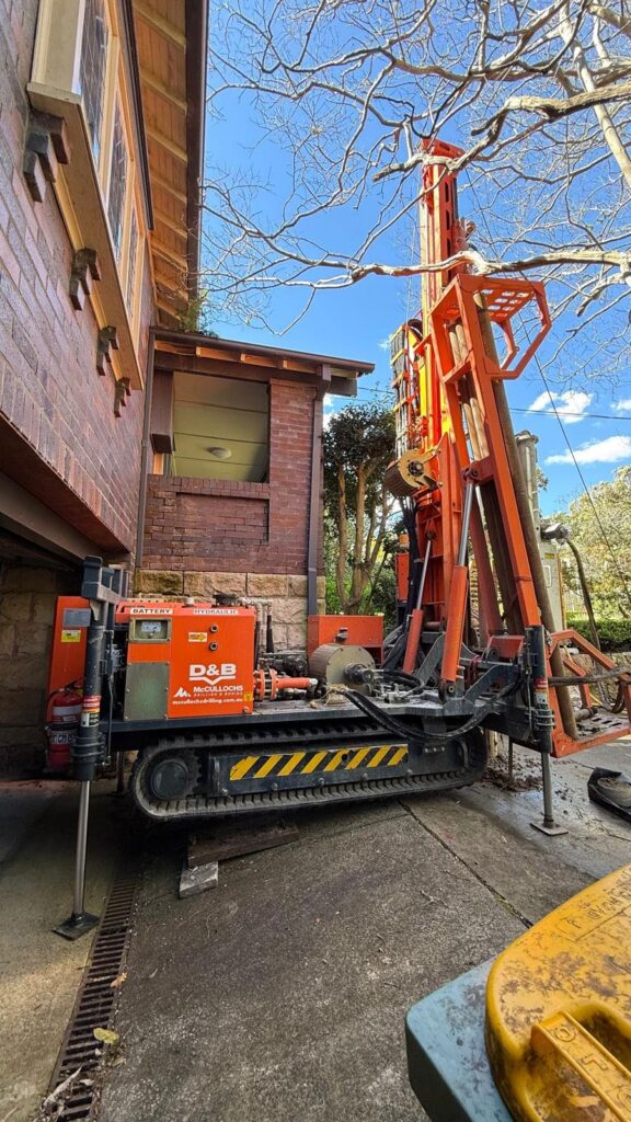 Hanjin DB8D tracked drilling rig set up in a narrow driveway beside a house