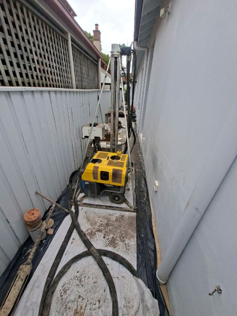 Christie hand portable drilling rig working in a narrow side passage between buildings